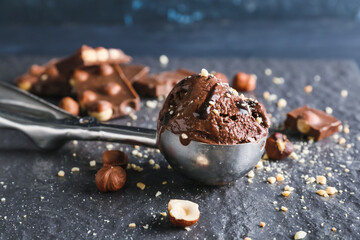 Scoop of tasty chocolate ice cream with nuts on table