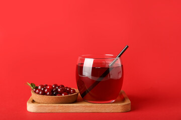 Glass of healthy juice and bowl with cranberries on color background