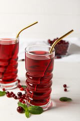 Glasses with healthy cranberry juice on light background