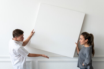 Blank frame being hung by a couple