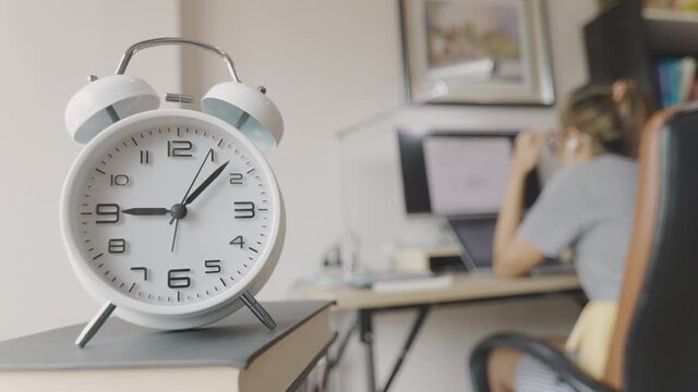 Time Lapse of clock moving fast in the morning during working rush hour with business woman working on computer and her desk at home shows concept of busy working with stress with time competition.