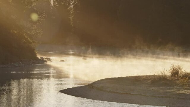 Sun rays shining on steam rising from the Snake River in Wyoming during color Autumn morning in the Teton Wilderness.