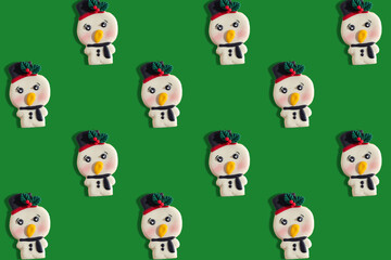 pattern of cookies in the shape of snowmen, on a flat green background