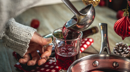 Woman is pouring fragrant hot punch into a clear mug. Concept of a cozy festive atmosphere, New Year and Christmas mood