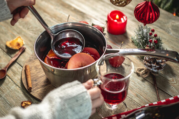 Woman is pouring fragrant hot glogg into a clear glass. Concept of a cozy festive atmosphere, New Year and Christmas mood