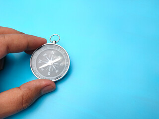 Hand holding compass on a blue background with copy space.y