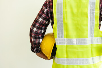 engineering concept construction worker holding a yellow hard hat and back view of the architect copy space