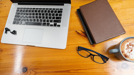 Laptop computer and eyeglasses and notebook with a coffee mug on business man's desk