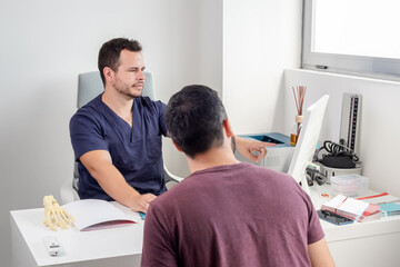 Physiotherapist explaining the evolution of a patient on a computer screen.