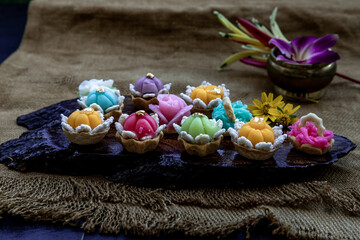A variety of elegantly beautiful Thai Desserts (Khanom Wan Thai) colorful variations serving in a dark wooden, The bites in gold color and different flower shapes, Thai dessert, Auspicious dessert, Ob