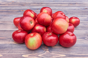A pile of red apples, collected in a rustic garden, lying on a wooden table.