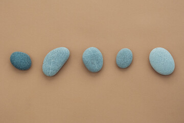 Set of sea stones of a round form on beige background. Top view of a collection of smooth pebbles.