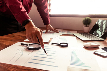 Business people use pen to point graphs to analyze company data and statistics from the chart.