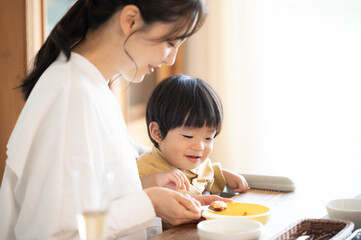 ご飯をあげる美しい日本人のママとアップの赤ちゃんコピースペースあり