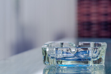 Ashtray for cigarette butt disposal, made of glass for aesthetic purposes.