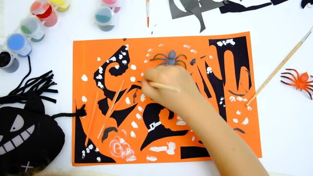 Child making card for the holiday of halloween. Funny crafts from pieces paper. Halloween decor. The concept for Halloween. DIY. 