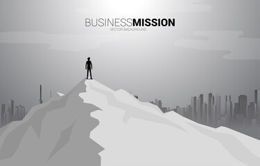 silhouette of businessman standing on the top of mountain and city background. Concept of Goal, Mission, Vision, Success in Career path.