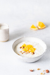 Fresh porridge on nut milk with baked oranges, orange jam and nuts on a gray background. Healthy breakfast, healthy food
