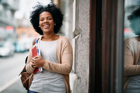 Happy African American mid adult student in front of the library.