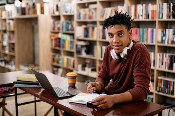 Smiling African American student learning in library and looking at camera.