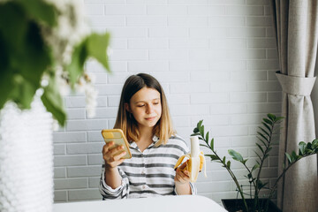 teenage girl talking on the phone and eating a banana