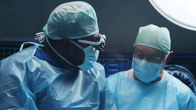 Multiracial team of professional medical surgeons performs the surgical operation in a modern hospital. Doctors are working to save the patient. Medicine, health and neurosurgery.