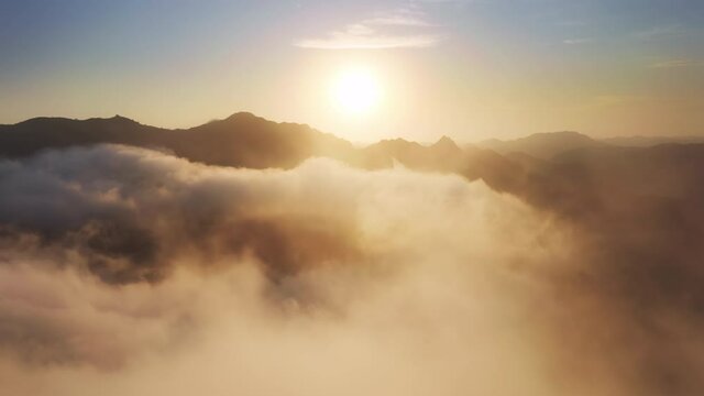 Flying through cinematic golden glowing cloudscape toward bright sunset sun. Flying in soft clouds. Aerial perspective view of flying over clouds. Sky with clouds and sun. Meditation dream footage 4K