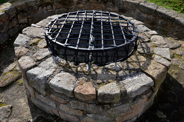 stone round fountain with a protective grid of twisted prisms. forged steel bars go spiraled at the...