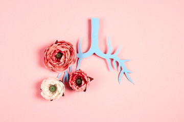 Symbol lungs made of paper and peony flowers on a pink background.