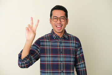 Fototapeta premium Adult Asian man smiling happy while giving victory finger sign