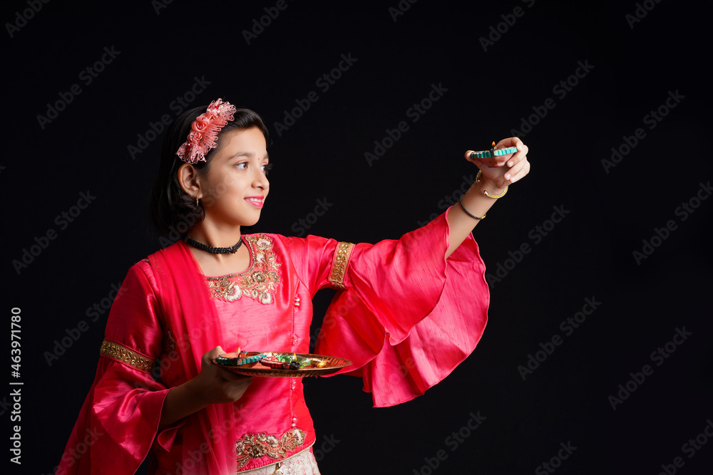 Wall mural Cute Indian little girl holding diya or oil lamps for Diwali Celebration.