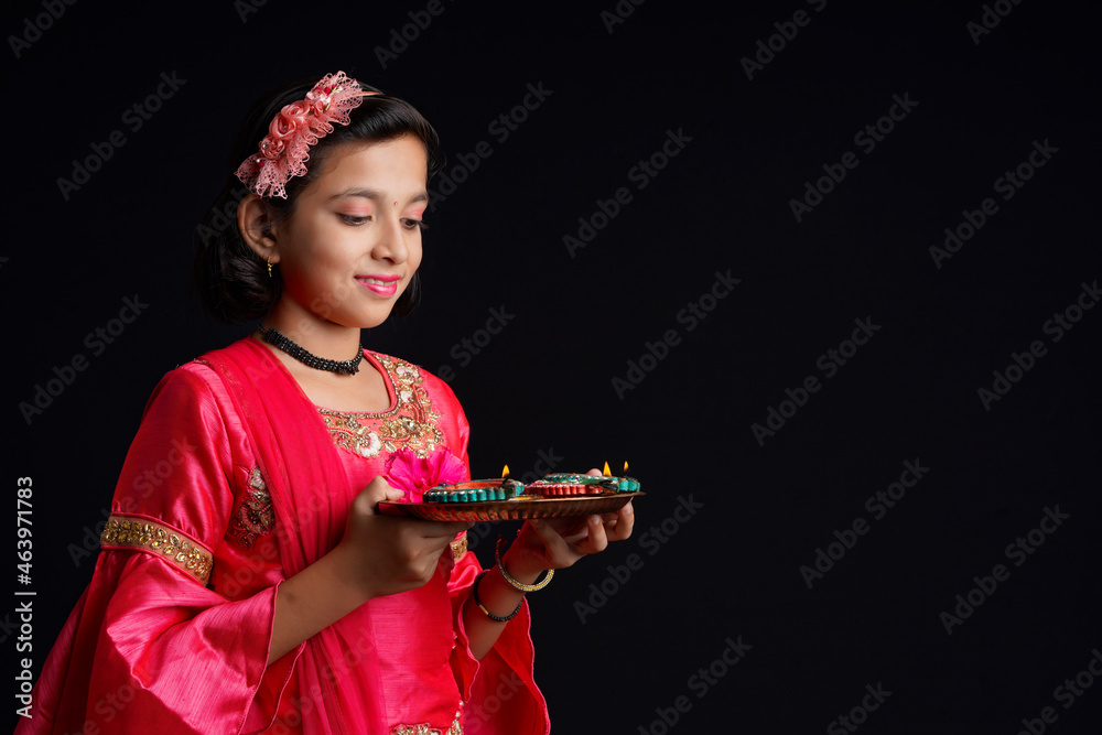 Poster Cute Indian little girl holding diya or oil lamps for Diwali Celebration.