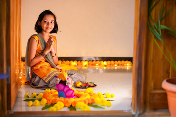 Cute indian little girl praying and celebrating diwali festival.