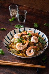 Stir fried noodles with pork, shrimp and vegetable on wooden table as traditional Chinese food