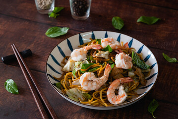 Stir fried noodles with pork, shrimp and vegetable on wooden table as traditional Chinese food