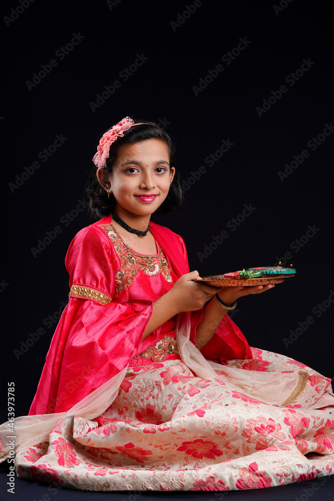 Wall mural Cute Indian little girl holding diya or oil lamps for Diwali Celebration.