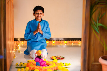 Cute indian little boy praying and celebrating diwali festival.