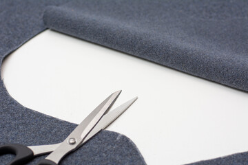 Metal scissors on a white table. A piece of gray drape fabric.