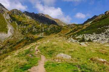 small path for hikers through green mountains with blue sky