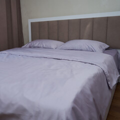 A large bed with light purple bedding(linens)