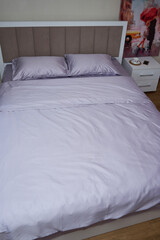 A large bed with light purple bedding(linens)