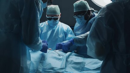 Multiracial team of professional medical surgeons performs the surgical operation in a modern hospital. Doctors are working to save the patient. Medicine, health, cardiology and transplantation.