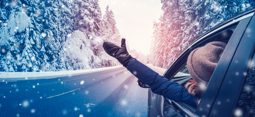 Happy woman in the car on the snowy background.