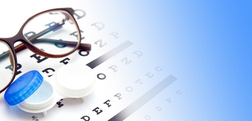 Contact lenses case and eye glasses on and eye test chart. Vision concept. Way to improve vision