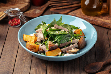 Bowl of healthy beef salad with potato and spinach on wooden background