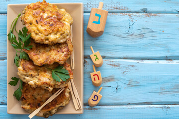 Wooden dreidels, chicken shawarma latkes for Jewish holiday Hanukkah on blue background with copy...