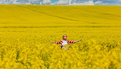 Woman in red and white striped jacket in rapeseed field
