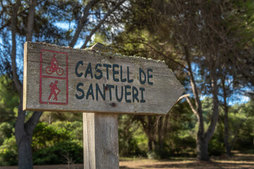 Close-up of the directional sign for the Santueri Castle, written in Catalan language, for hikers and walkers. Image of adventure tourism. Island of Mallorca, Spain