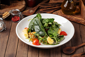 Healthy spinach salad with eggplant and baby corn on wooden background