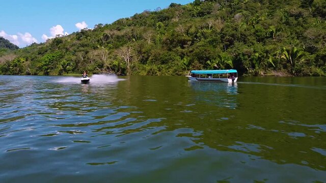 Drone shot near water cross with a jet ski that forms a rainbow with lake water. Lake in the peruvian jungle. Amazonas